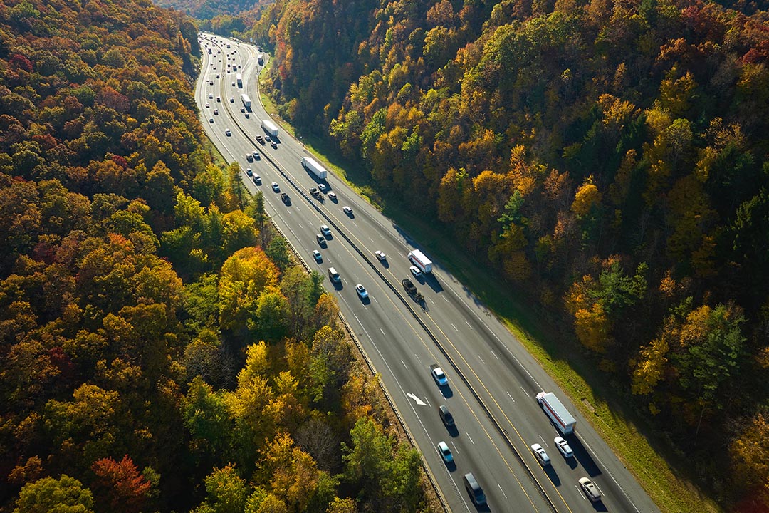 I-40 freeway in North Carolina leading to Asheville through Appalachian mountains in golden fall with fast moving trucks and cars. Interstate transportation concept.